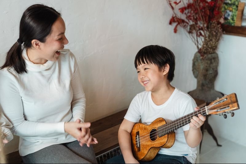 kid with mother playing ukulele
