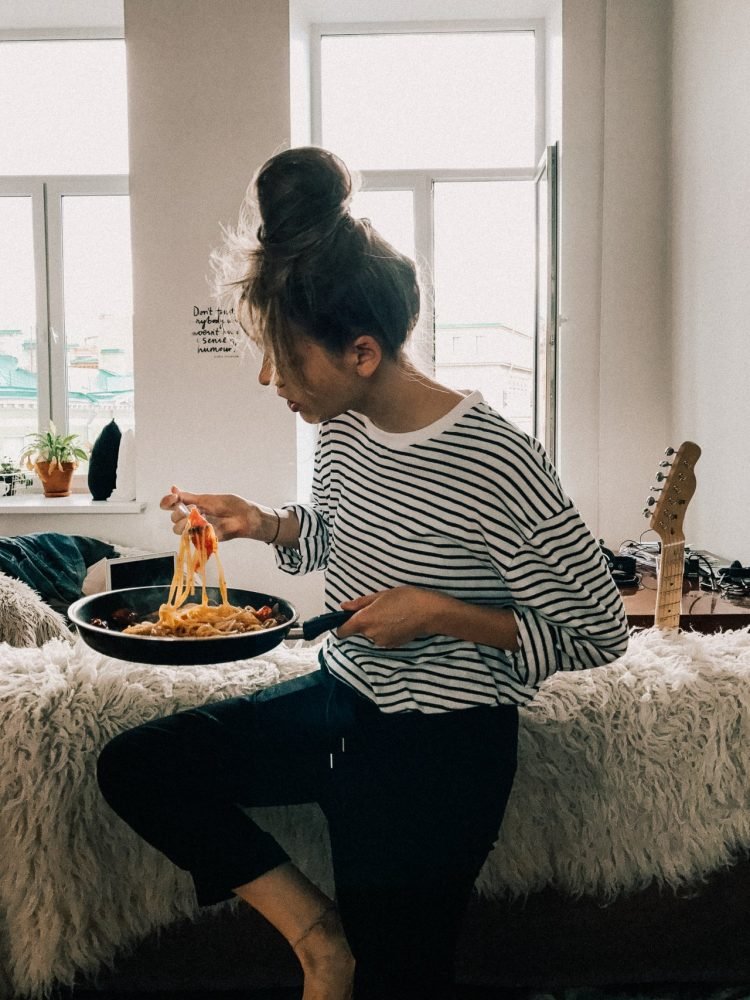 woman-in-black-and-white-striped-shirt-eating-food-from-pot